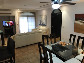 Un salon moderne comprenant un canapé, une table à manger, des chaises et un téléviseur.