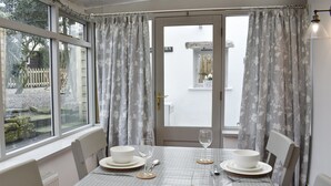 A dining area with a table set for four, a view of the garden through the window, and a door leading outside. - 2 bedroom accommodation in Melmerby, near Penrith (Melmerby, near Penrith)
