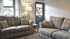 A living room with two sofas, a small table, a lamp, and a door with a heart-shaped decoration. - 2 bedroom accommodation in Melmerby, near Penrith (Melmerby, near Penrith)
