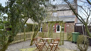 A garden patio with a wooden table and chairs, surrounded by a gravel path and a wooden fence. - 2 bedroom accommodation in Melmerby, near Penrith (Melmerby, near Penrith)