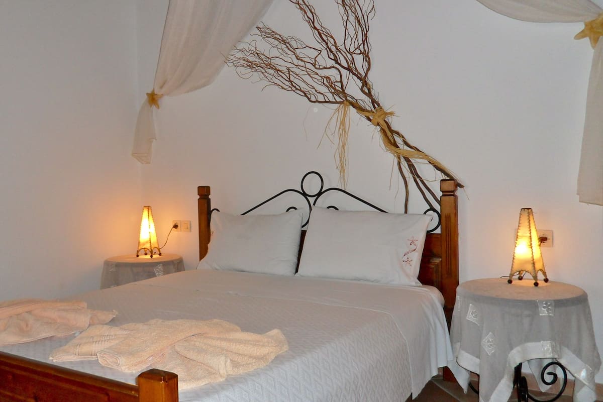 A bed with white linens, two bedside tables with lamps, and a canopy over the bed.