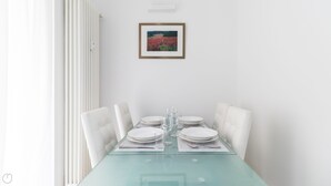 A dining area with a glass table, white chairs, and a framed picture on the wall. - Italianway - Corso Genova 27 A (Milan)