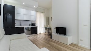 A modern living room with a sofa, a TV, and a dining area with a table and chairs. - Italianway - Corso Genova 27 A (Milan)