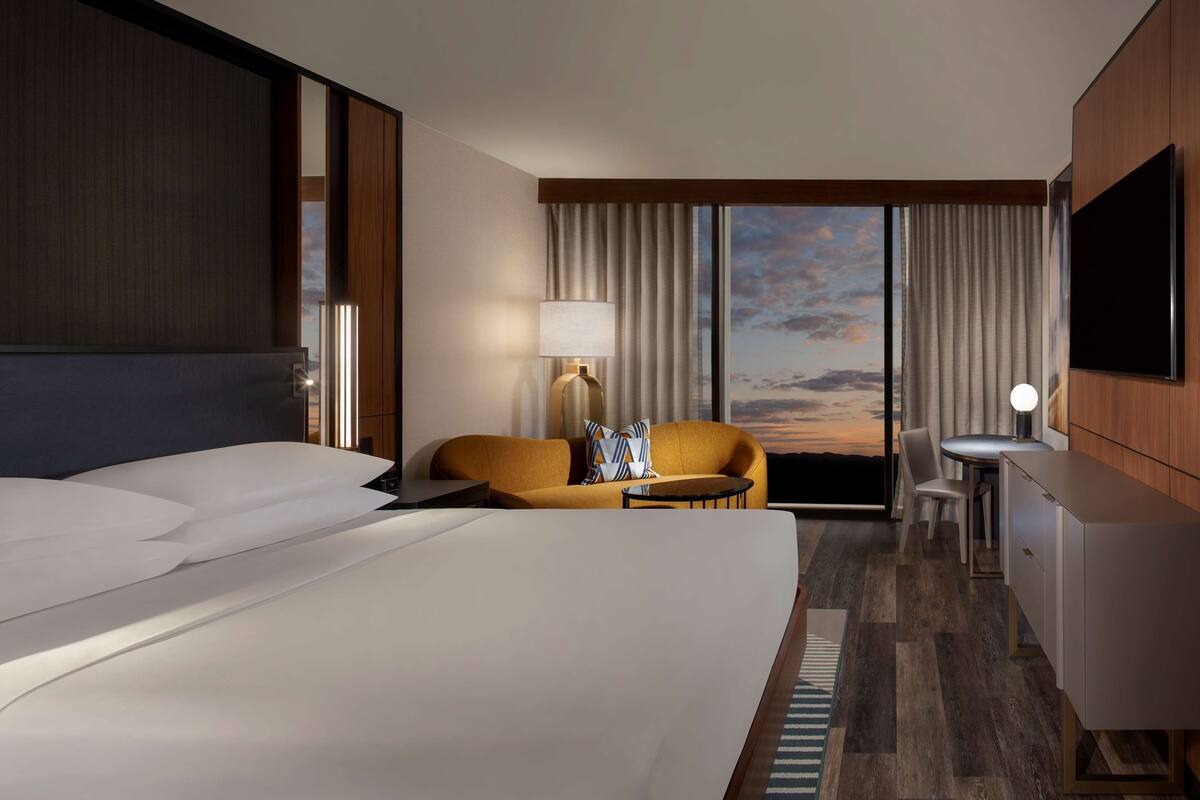 Een hotelkamer met een groot bed, een slaapbank, een bureau en een televisie.