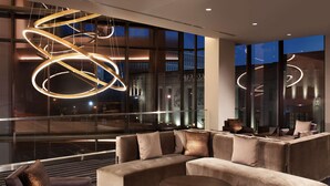 Un hall d’hôtel moderne, doté d’un grand canapé d’angle, d’une table ronde et d’un luminaire original en forme de spirale.