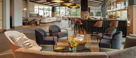 A spacious lobby with a bar area, comfortable seating, and large windows providing natural light.