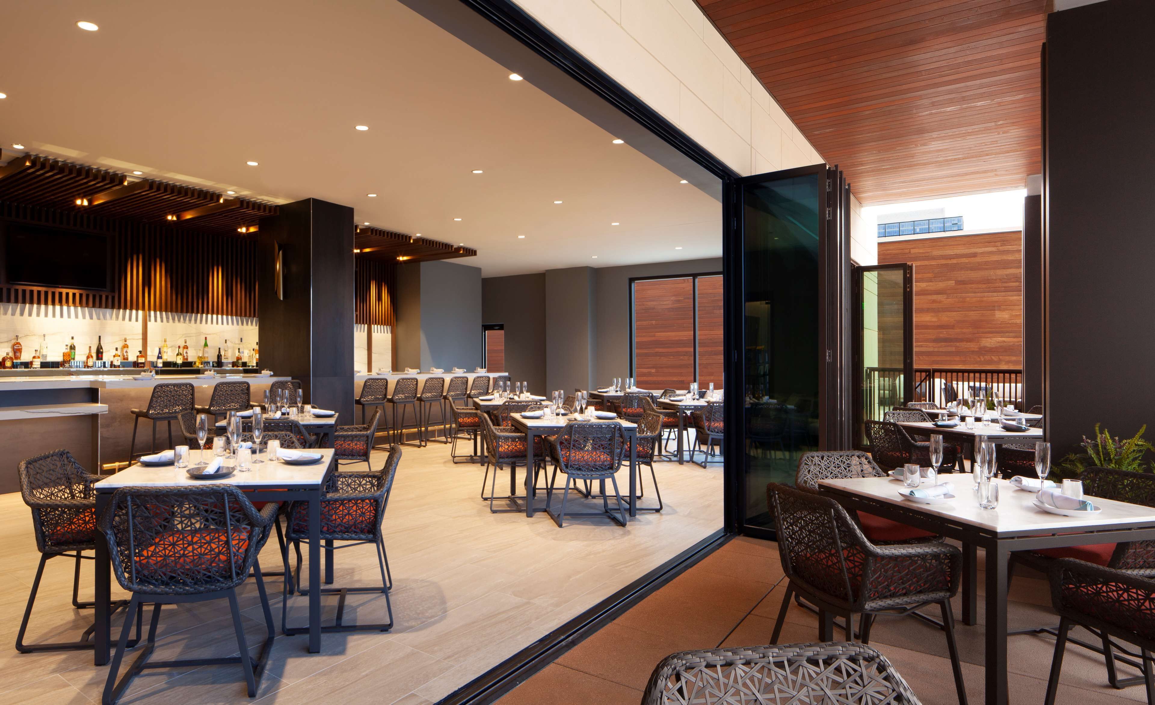 Un restaurant moderne doté d’un bar, de plusieurs tables et de chaises.