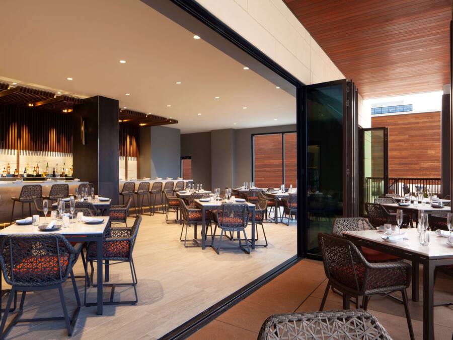 Un restaurant moderne doté d’un bar, de plusieurs tables et de chaises.