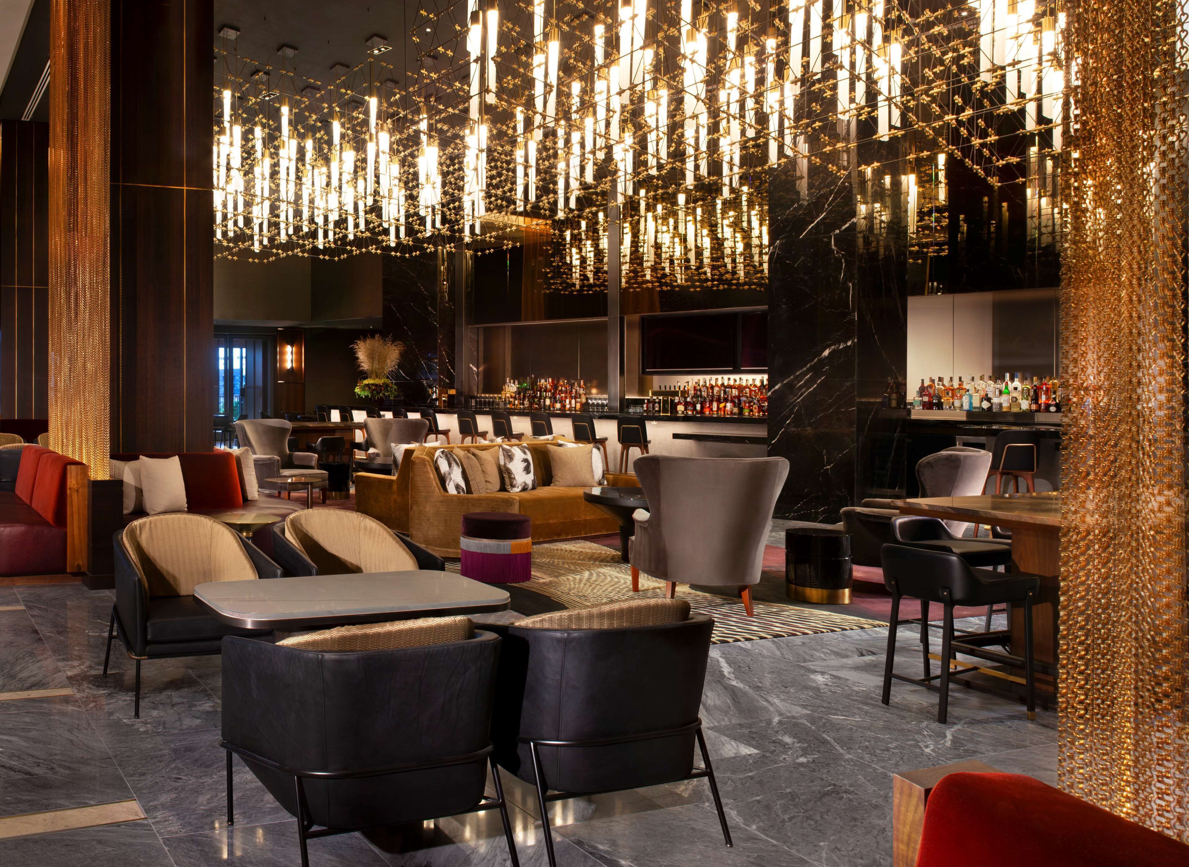 A modern lounge area with seating, a bar, and a chandelier.