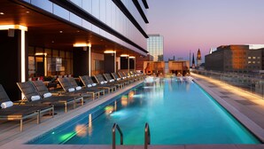 Un espace piscine moderne avec des chaises longues et une vue sur les gratte-ciel de la ville.