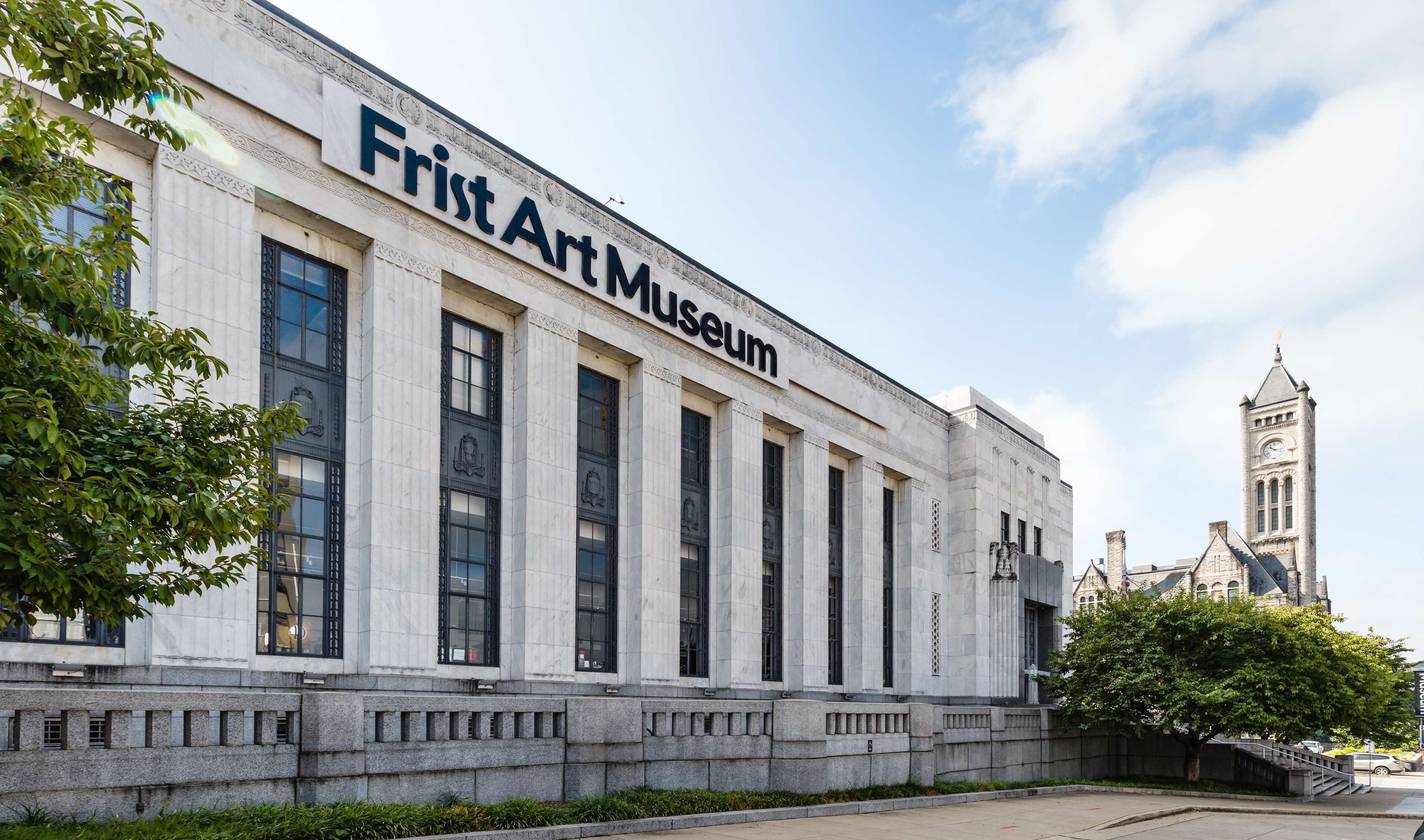 The exterior of the Frist Art Museum with classical architecture, large windows, and a clock tower in the background.