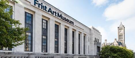 The exterior of the Frist Art Museum with classical architecture, large windows, and a clock tower in the background.
