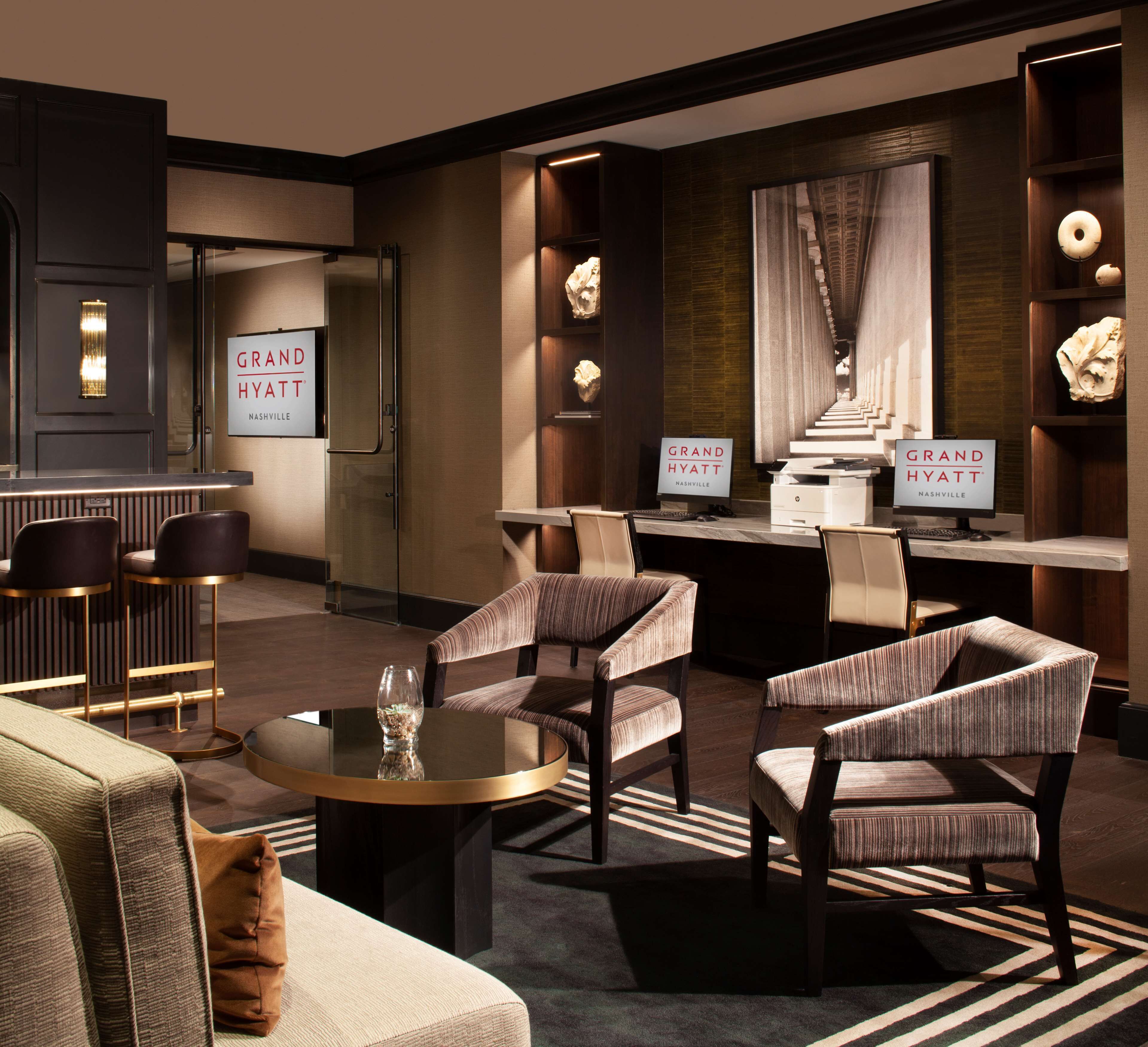 A modern lobby with seating, a reception desk, and signs for Grand Hyatt Nashville.