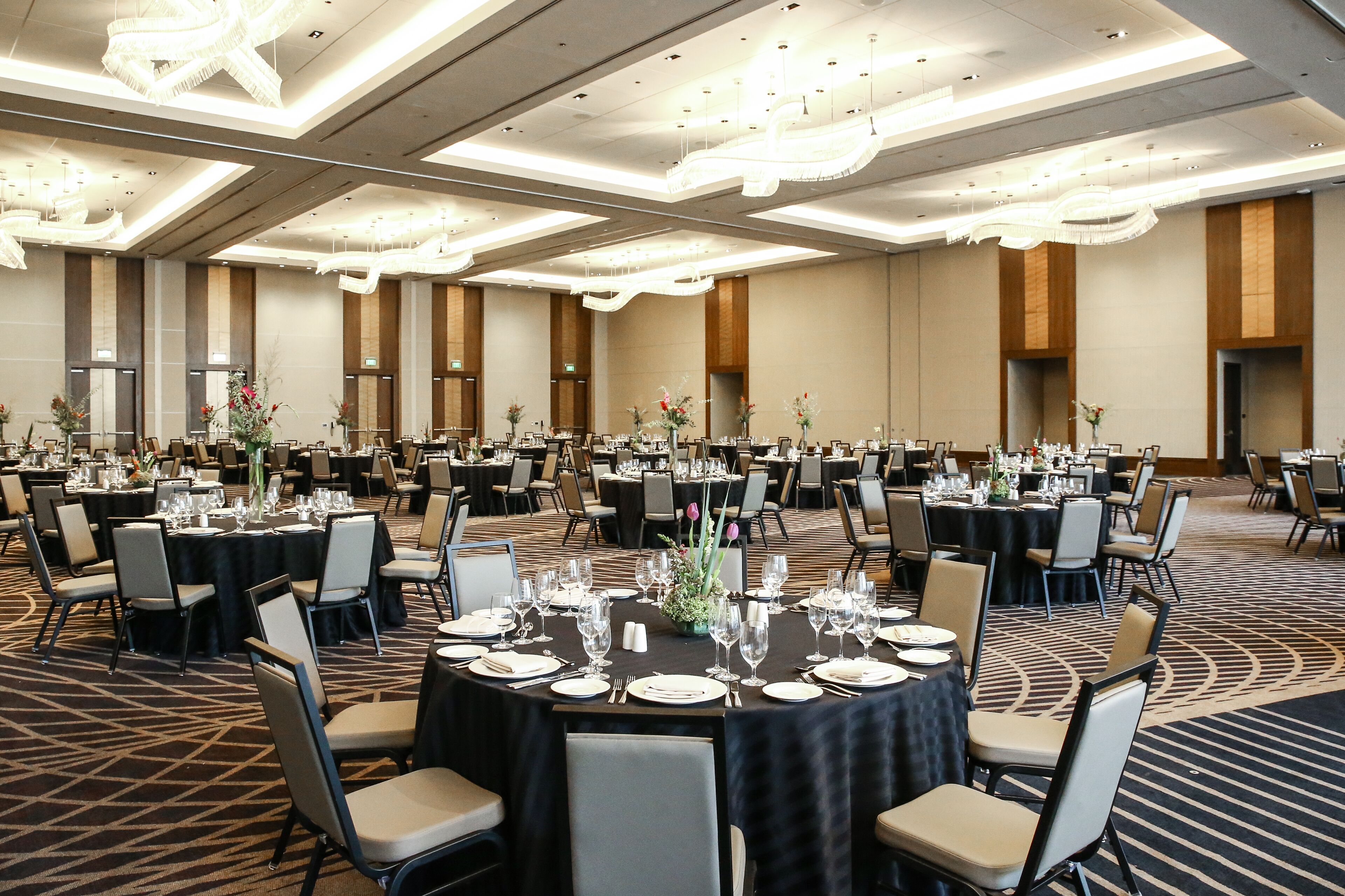 A large banquet hall with multiple round tables set for dining, each with chairs and table settings.