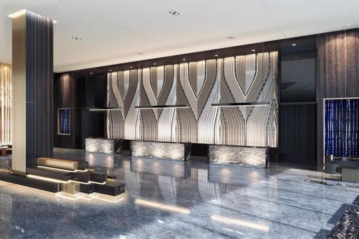 Een moderne lobby met een marmeren vloer, een receptiebalie en een behang met patroon.