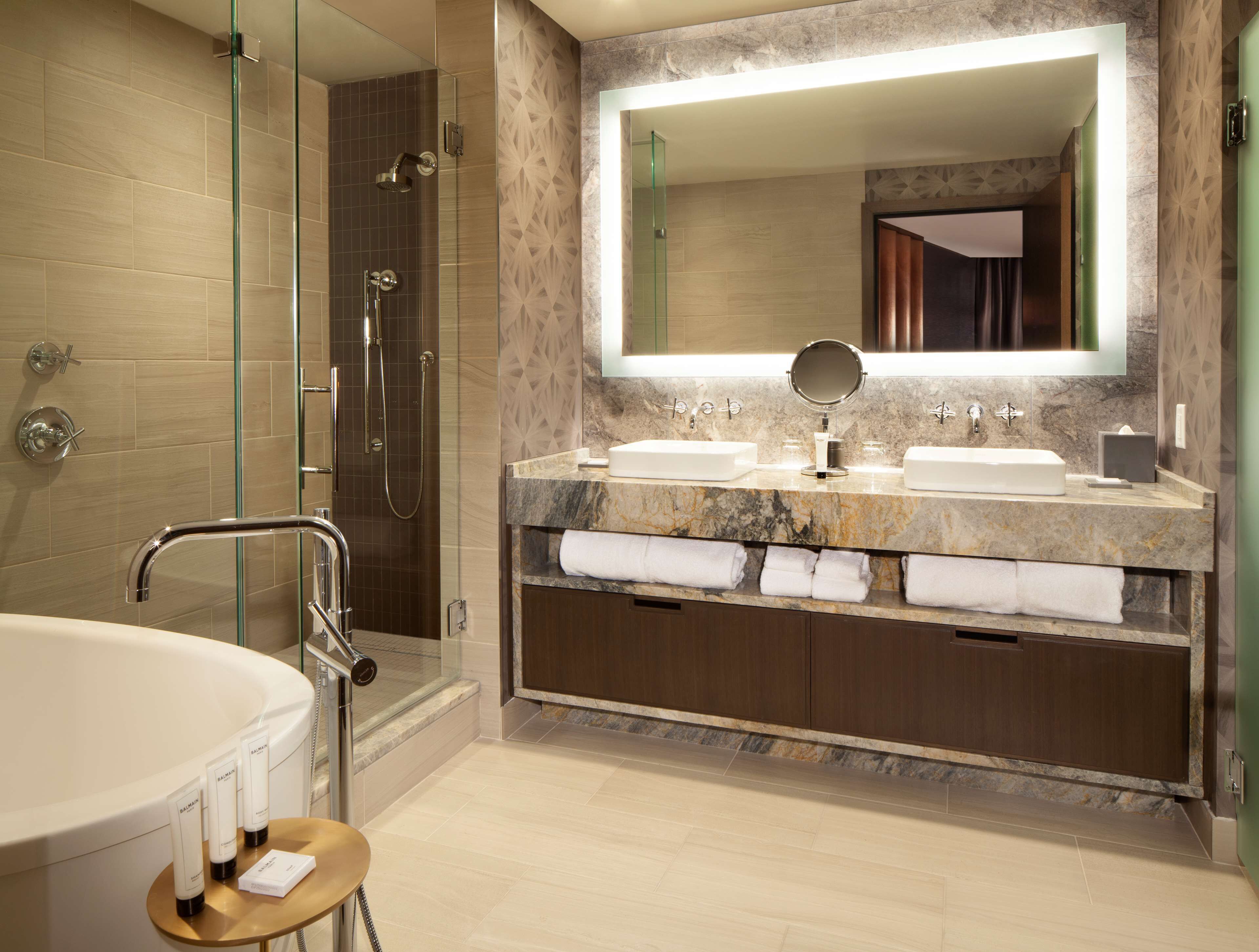 Un bagno moderno con doccia a vetro, una vasca freestanding e un mobile lavabo con due lavandini e uno specchio grande.