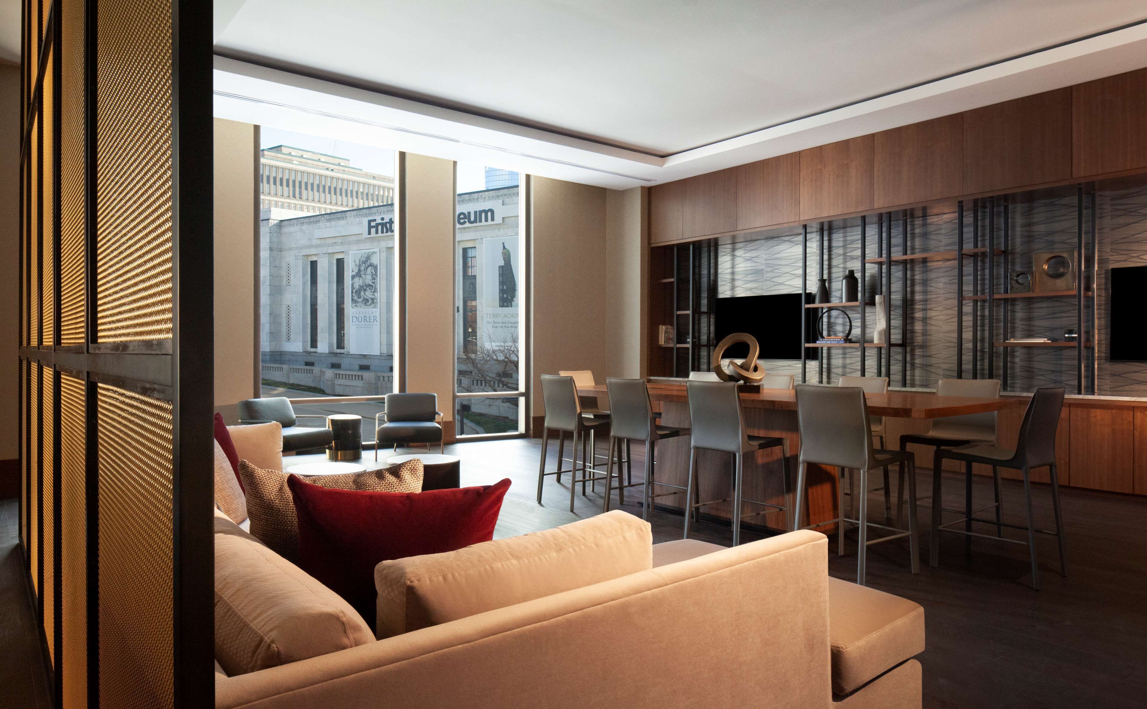 A modern living room with a dining area, large windows, and a view of a building.