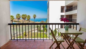 Ein Balkon mit Meerblick, einem Tisch mit Stühlen und einem Blumentopf.