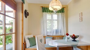 Un rincón comedor acogedor con un banco de madera, sillas blancas, una mesa con mantel a rayas y un cuenco decorativo sobre la mesa.