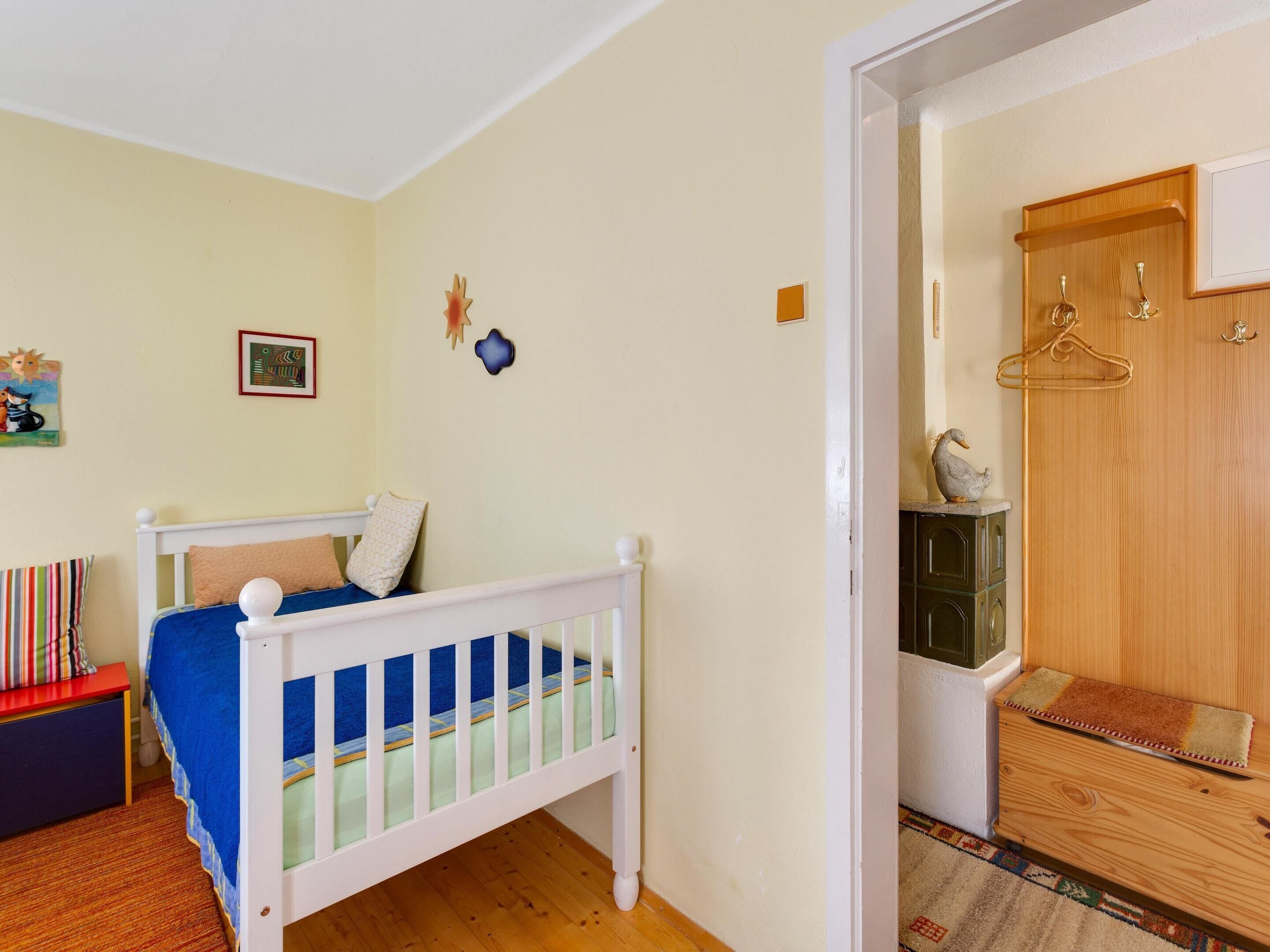 A child's room with a white crib, a small table, and a door leading to a bathroom.