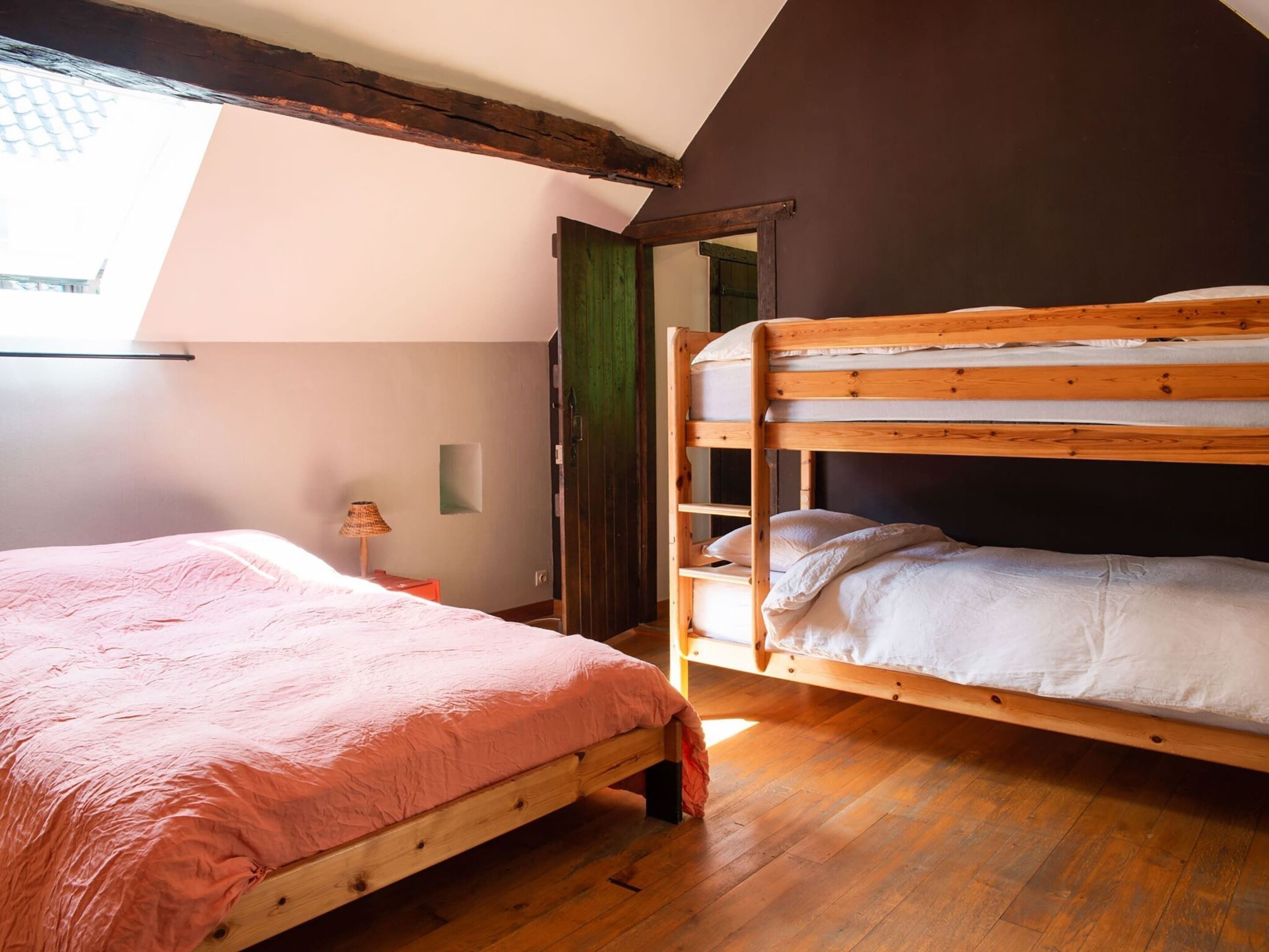 Un dormitorio con literas, una cama individual, suelo de madera, una lámpara y vistas al exterior.