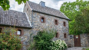 Un bâtiment en pierre avec un toit en tuiles, un chemin de gravier et un portail portant l’inscription « VIE RURALE ».
