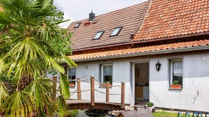 A house with a tiled roof, a small pond, and a wooden structure. - Ferienhaus in Meisdorf (Falkenstein)