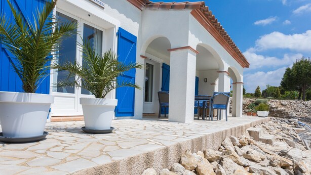 A building with white walls, blue shutters, and a stone-paved entrance. - Modern Villa in Camplong With Private Pool (Felines-Minervois)