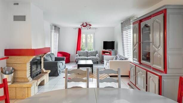 Una sala de estar con chimenea, sofá, televisor y un comedor.