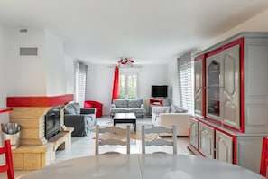 Un salon avec une cheminée, un canapé, un téléviseur et un coin repas.