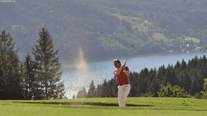 A golf course with a water body and forested hills in the background. - Farmhouse in Fresach Near Millstatt Lake (Fresach)