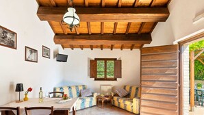 A cozy room with a wooden ceiling, a dining table with chairs, a sofa, and a window with shutters. - Tranquil Stay in the Heart of Umbria (Città di Castello)
