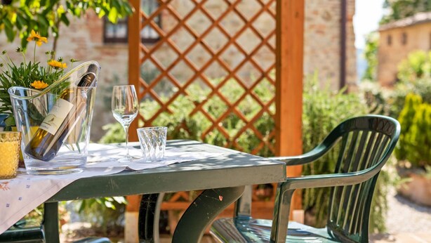 A table set outdoors with a bottle of wine, a glass, and a glass of water. - Tranquil Stay in the Heart of Umbria (Città di Castello)