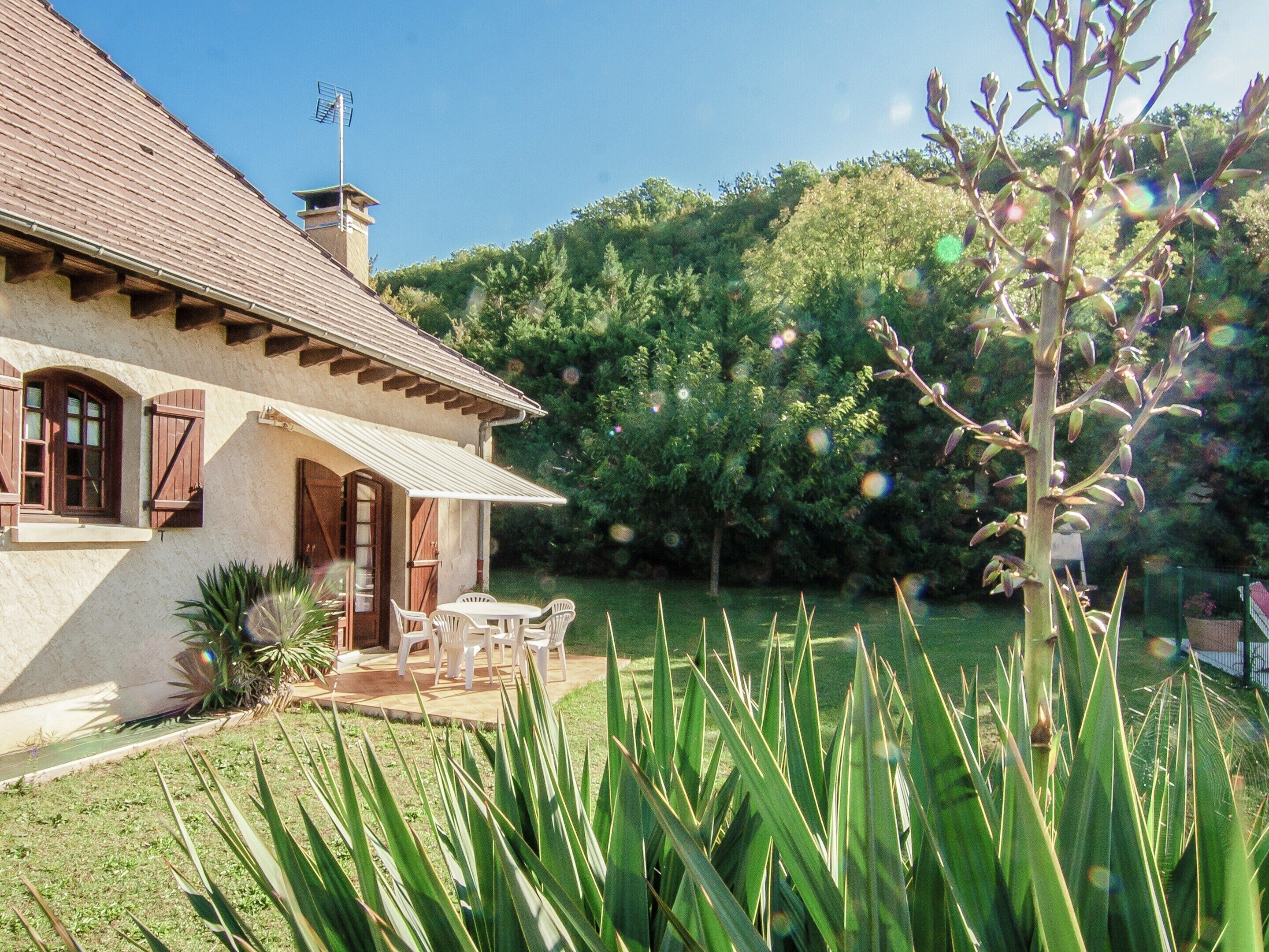 A house with a tiled roof, a chimney, and a patio with chairs and a table.