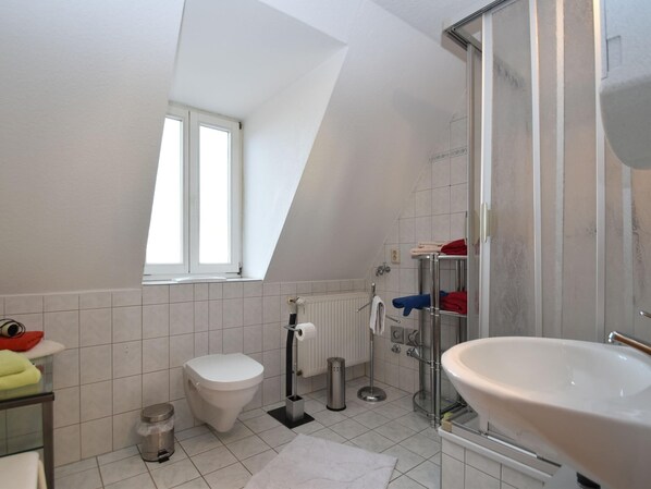 Een moderne badkamer met douche, toilet en wastafel.