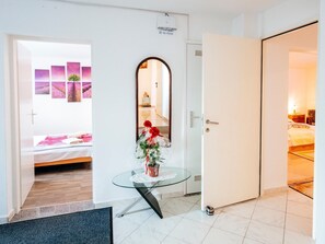 A hotel room with a bed, a glass table with a vase of flowers, a white door, and a view of another room. - Beautiful Holiday Home in Maslenica Near Beach" (Jasenice)