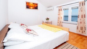 A bedroom with a bed, a small table with flowers, a window with curtains, and a painting on the wall. - Beautiful Holiday Home in Maslenica Near Beach" (Jasenice)
