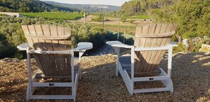 Two Adirondack chairs facing a vineyard with a river and hills in the background. - Villa in Provence With Pool and Vineyard Views (Saint-Antonin-du-Var)