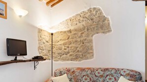 Una sala de estar con pared de piedra, televisor de pantalla plana y sofá estampado con motivos florales.