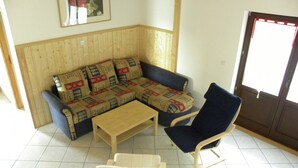 Un salón con sofá, sillón y una mesa de centro.