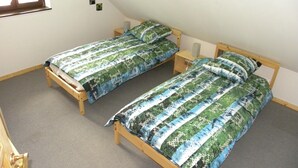 Dos camas individuales con cabeceros de madera, una ventana pequeña y suelo cubierto de alfombra.