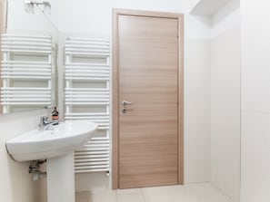 Un baño con un lavabo blanco, un espejo y una puerta de madera.