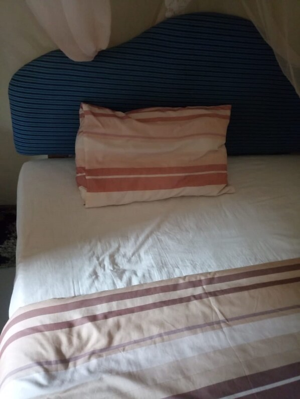 A bed with a striped bedspread and a pillow with horizontal stripes.