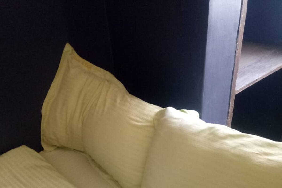 A bed with a white mattress and pillows, a dark headboard, and a window with a view of a building.