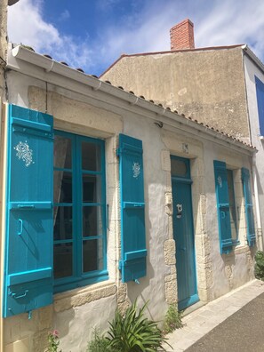Um edifício com portadas azuis, chaminé visível e fachada de pedra.