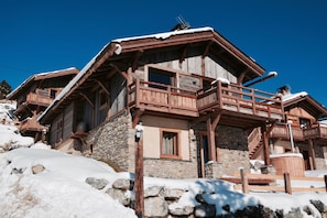 Un chalet en bois avec des fondations en pierre, des balcons en bois et un escalier en pierre.