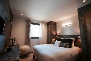 Une chambre à coucher avec un grand lit, une tête de lit en bois, une table de chevet avec une lanterne et un tapis moelleux.