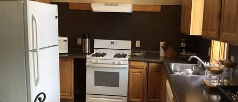 Efficient kitchen with stove, oven, and sink, featuring a refrigerator and coffee maker.
