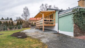 Une cabane en bois dotée d’un balcon, d’une allée en gravier et d’un mur végétal recouvert de lierre.