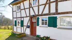 A traditional half-timbered house with a red door, green shutters, and a small garden area with planters. - Chalet in Korbach Nahe Skigebiet Willingen (Korbach)